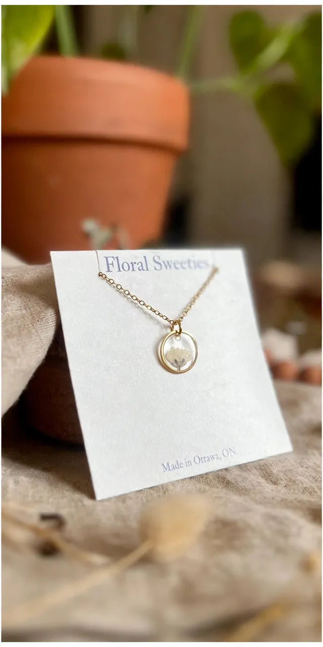Baby's breath pendant necklace close-up with soft focus terracotta pot behind