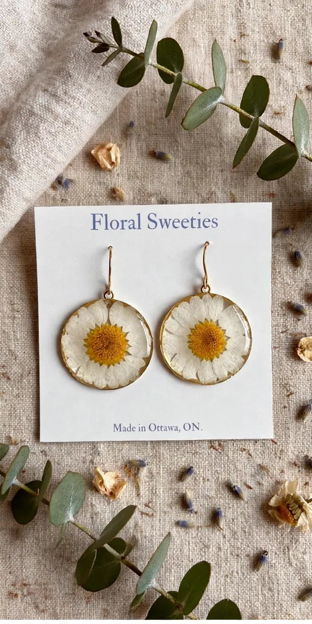 Daisy dangle earrings front view close-up showing the pressed daisy centers in resin