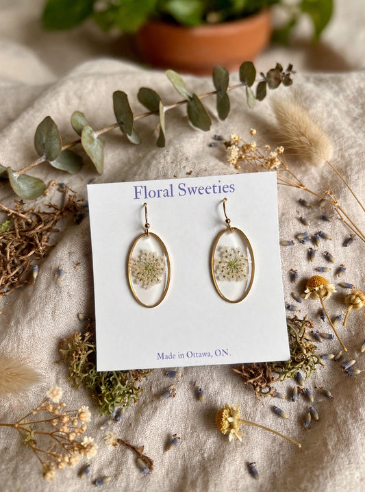 Dangle earrings with real Queen Anne's lace flowers in resin on a display card, styled on linen