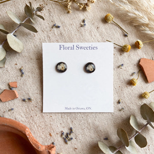 Stud earrings with real baby's breath flowers in resin on a display card, styled on linen