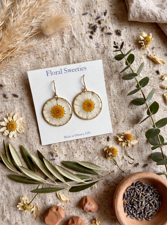 Daisy dangle earrings angled view with a bowl of lavender buds and dried daisies on linen