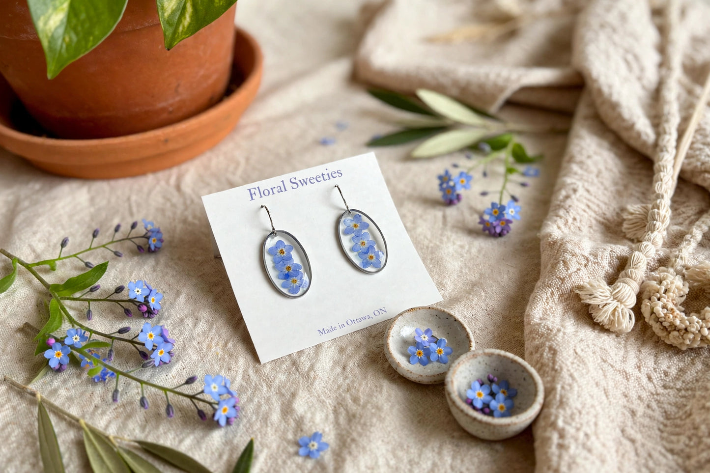 Forget-me-not dangle earrings with small bowls of fresh forget-me-nots, angled view