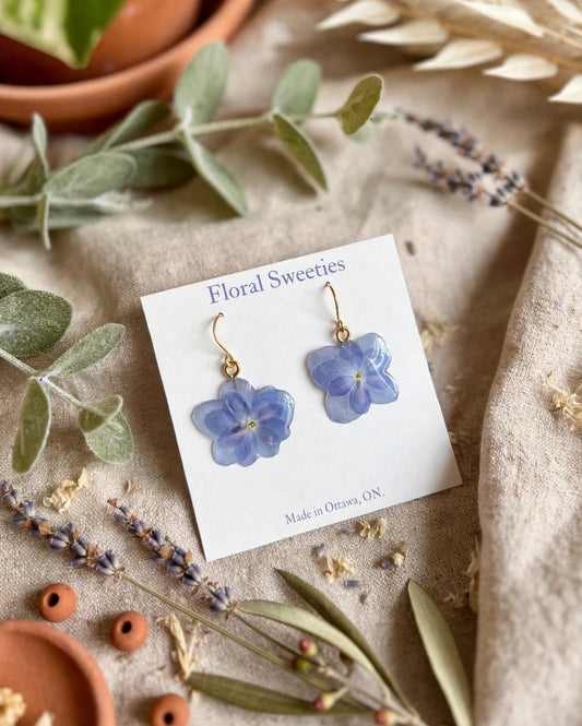 Blue hydrangea flower dangle earrings angled view on their display card with lavender