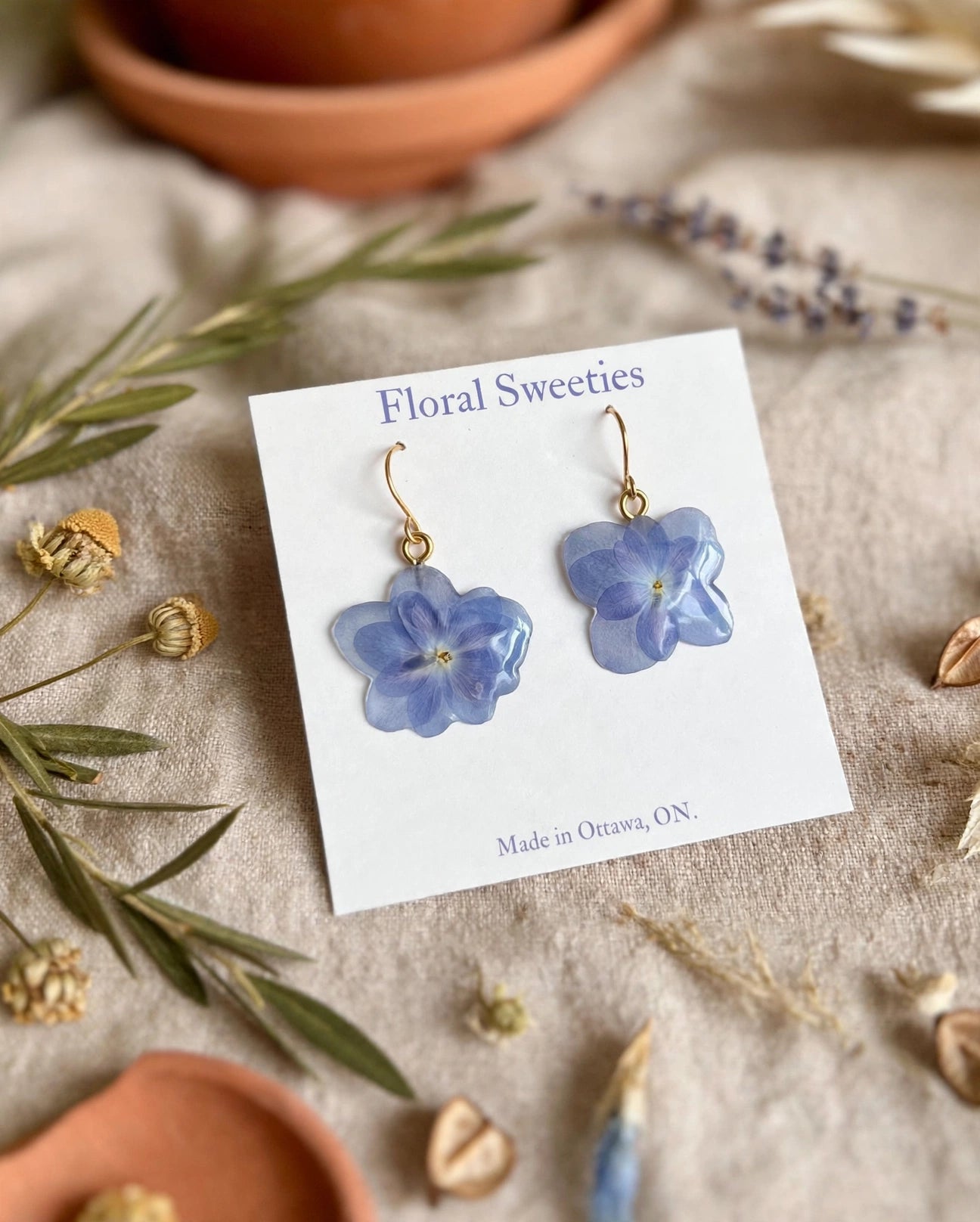 Close-up of blue hydrangea resin dangle earrings showing the flower shape detail