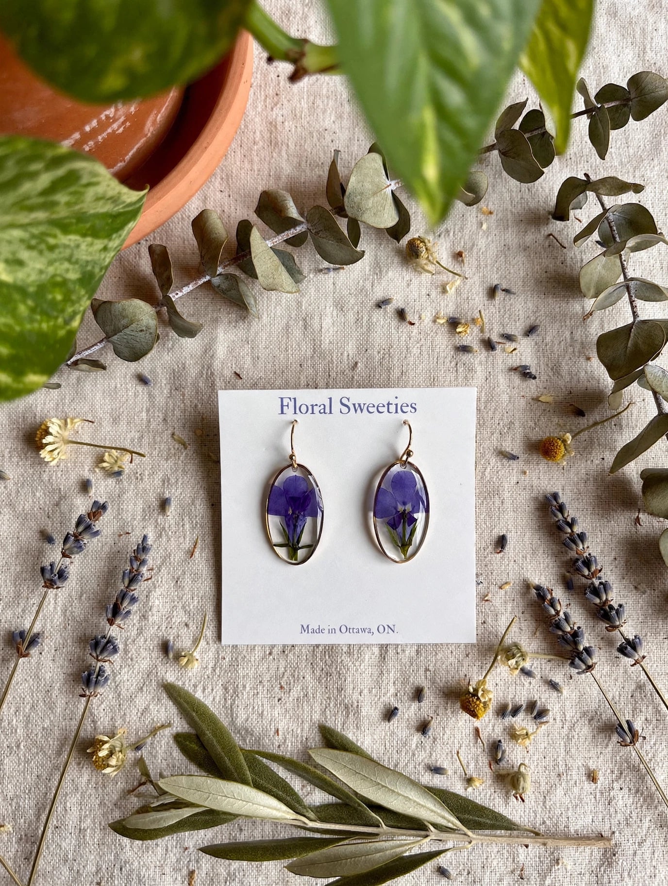 Lobelia dangle earrings styled with lavender and greenery on linen, overhead view
