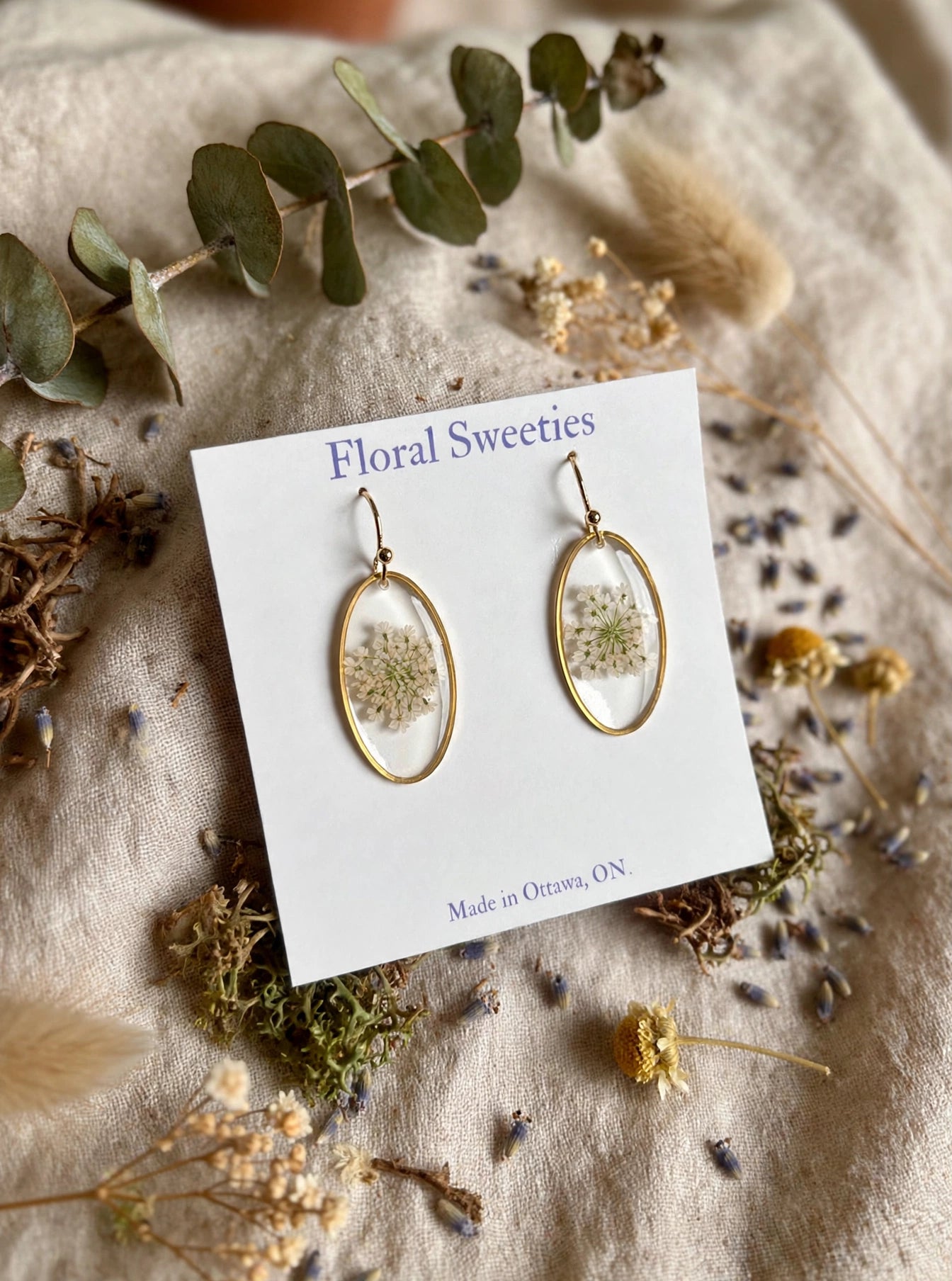 Queen Anne's lace oval dangle earrings angled view with moss and lavender on linen